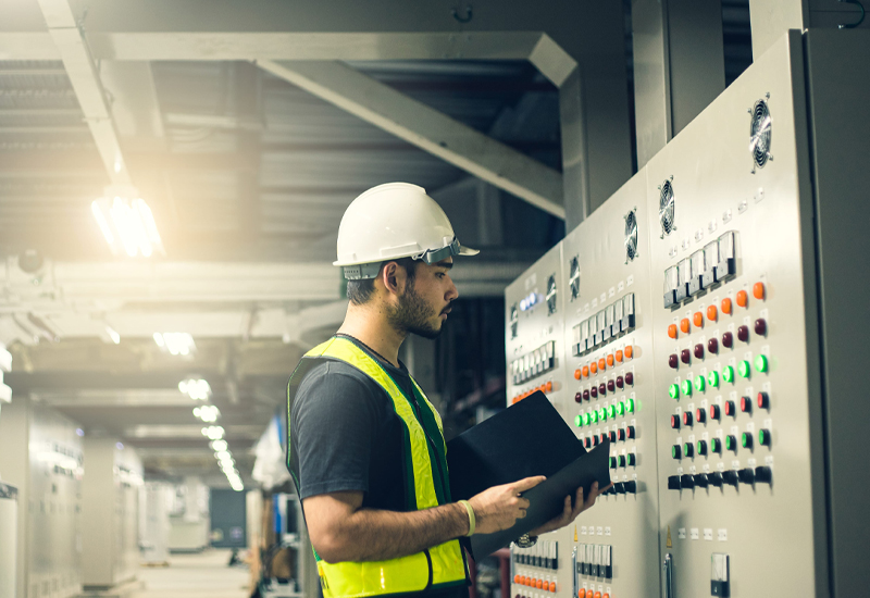 Engineer reviewing an industrial control panel for IEC 61511 and ISA 84 safety system requirements.